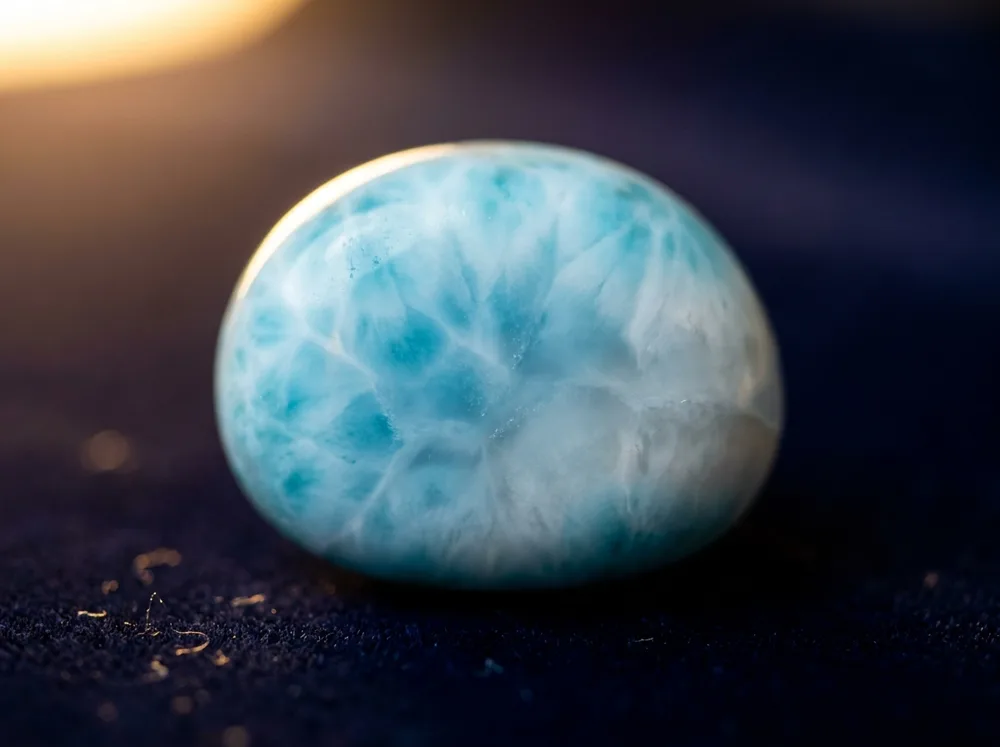 Uma larimar sobre um fundo azul marinho à meia-noite, iluminada com luz dourada e quente
